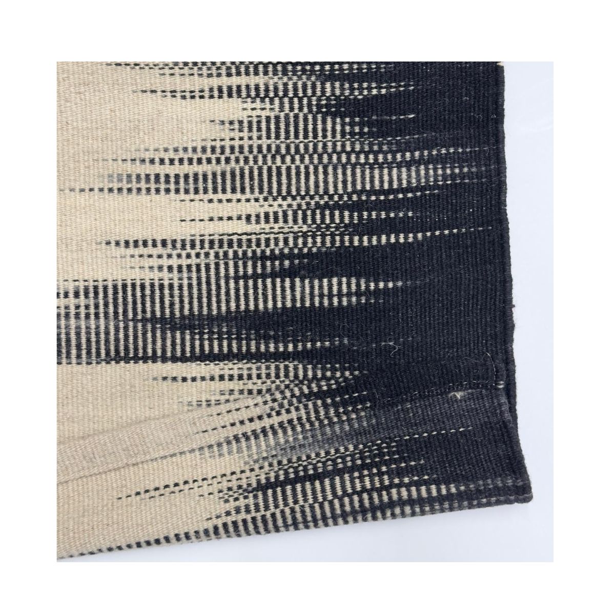 Close-up de um tapete tecido à mão em preto e branco com design moderno e dinâmico.