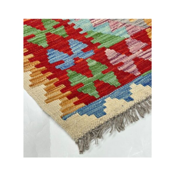 Tapete artesanal colorido em estilo kilim com desenhos geométricos e franjas.