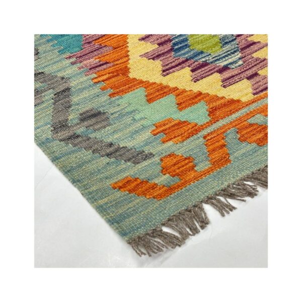 Tapete artesanal multicolorido com motivo tribal e franjas cinza.