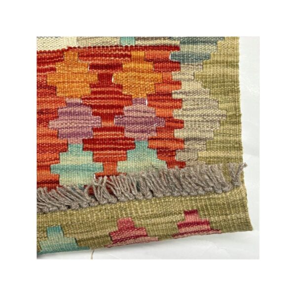 Tapete kilim artesanal com motivos geométricos em cores vibrantes e tons terrosos.
