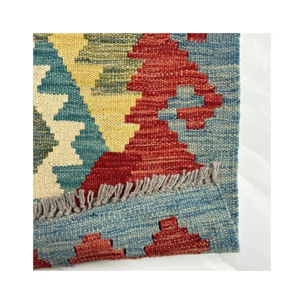 Tapete tecido à mão em estilo kilim com padrão geométrico colorido e acabamento em franja.
