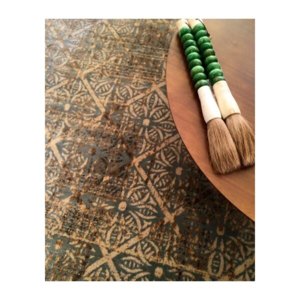 Conjunto artesanal com tapete geométrico e pincéis decorativos com contas verdes.
