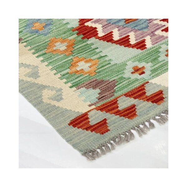 Close-up de tapete tradição Kilim com padrões geométricos e florais vibrantes em vários tons.