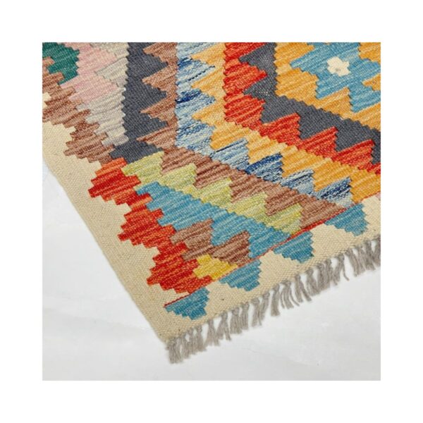Tapete artesanal vibrante com padrão geométrico e franjas em estilo Kilim.