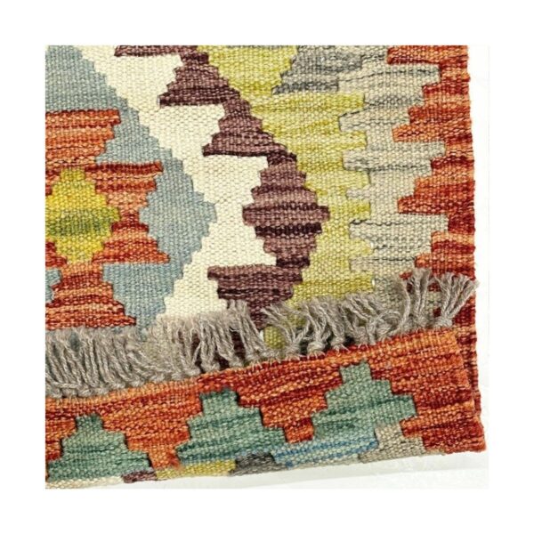 Tapete kilim tecido à mão com padrões geométricos em tons terrosos e franja cinza.