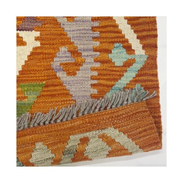 Tapete kilim artesanal em tons terrosos com padrões geométricos e franja cinza.