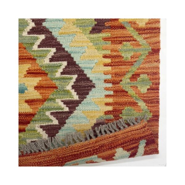 Tapete kilim artesanal com padrões geométricos e uma paleta de cores terrosas vibrantes.