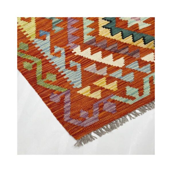 Tapete artesanal com padrões geométricos e cores vibrantes em fundo laranja.