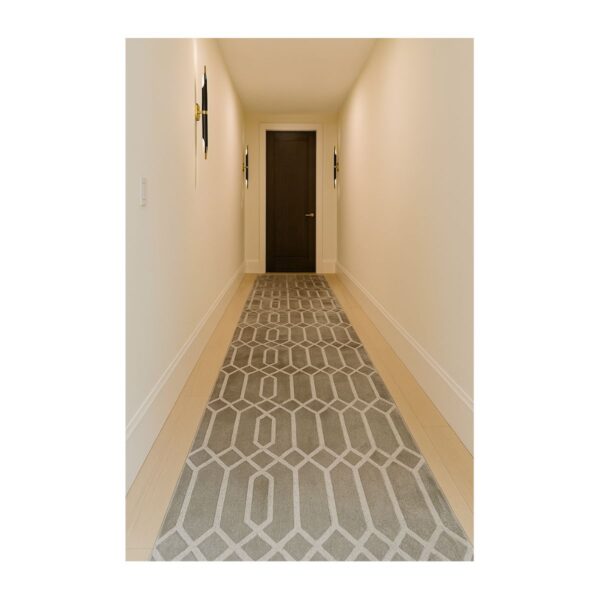 Corredor moderno minimalista com iluminação indireta e tapete geométrico cinza.