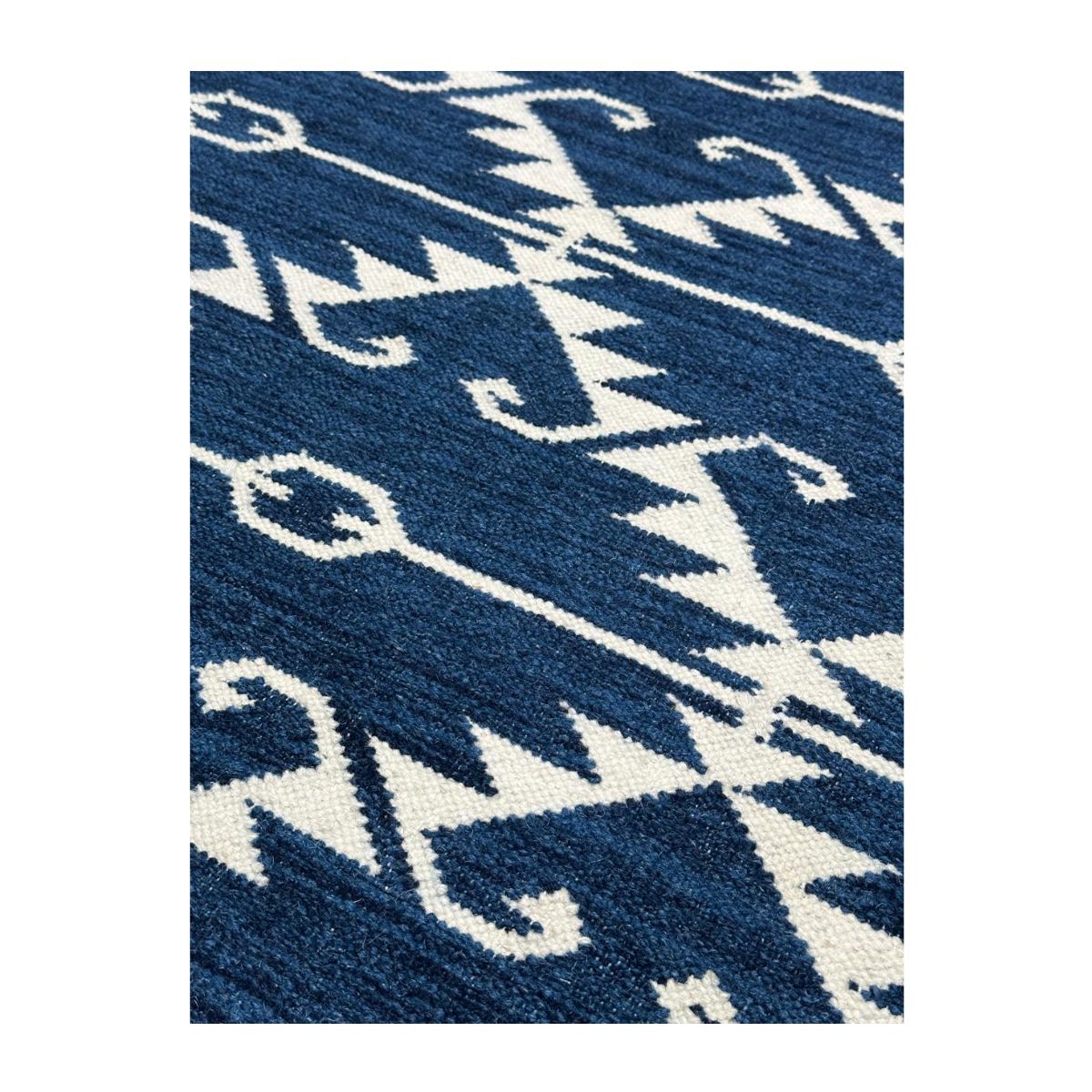 Tapete geométrico artesanal em azul profundo e detalhes brancos.