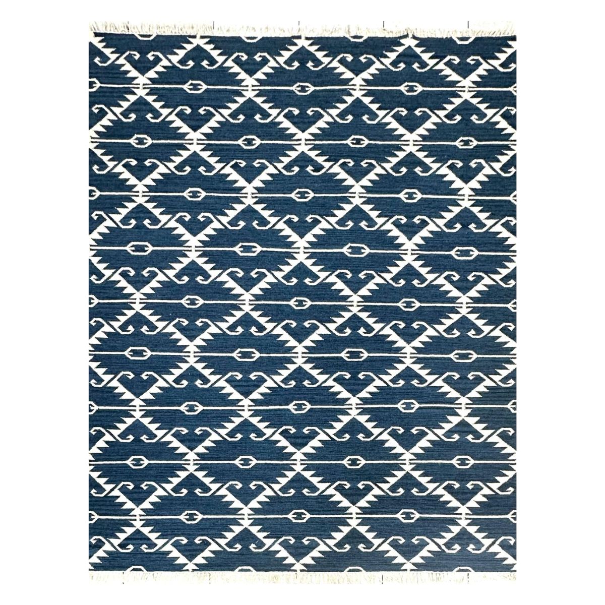 Tapete artesanal azul e branco com design geométrico e franjas.